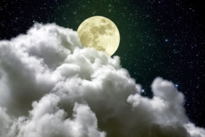 Beautiful full moon rising over a big white cloud in a beautiful cloudy night